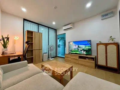 Modern living room with stylish furniture and large TV, featuring air conditioning and wooden accents.