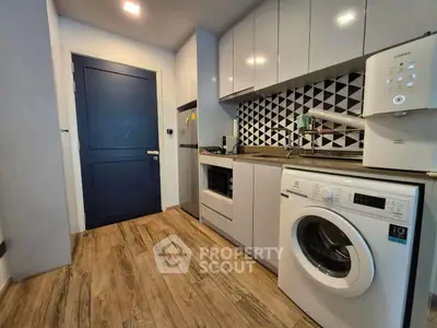 Modern kitchen with washing machine and stylish backsplash in compact apartment.