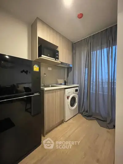 Modern compact kitchen with washing machine and sleek appliances in cozy apartment.