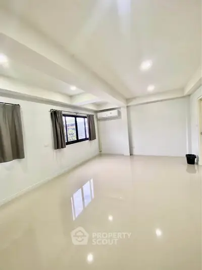 Spacious unfurnished living room with large window and modern lighting