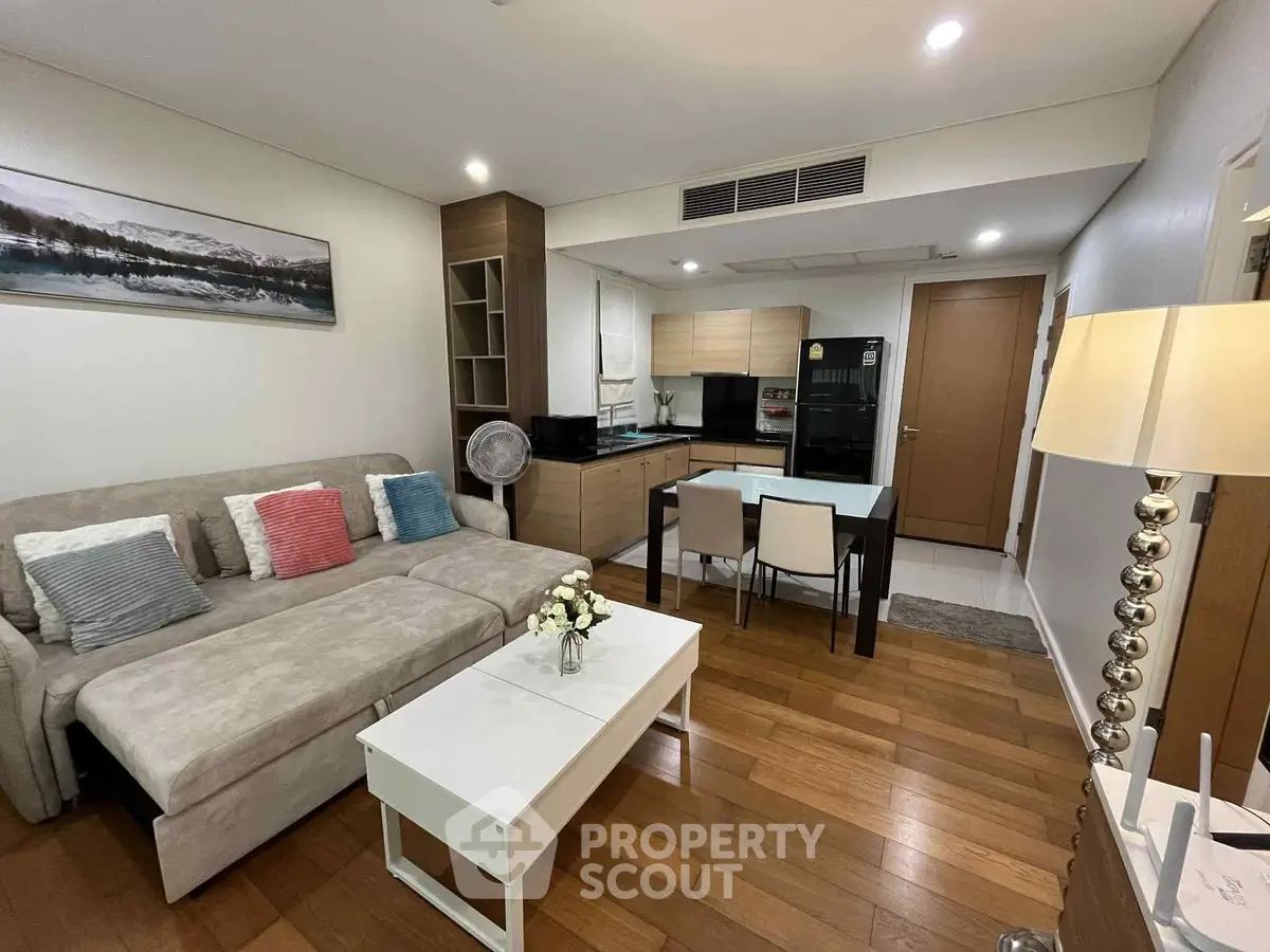 Modern living room with cozy sofa, dining area, and stylish kitchen in open layout apartment.