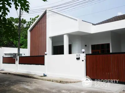 Modern white house with wooden accents and gated entrance in a serene neighborhood.