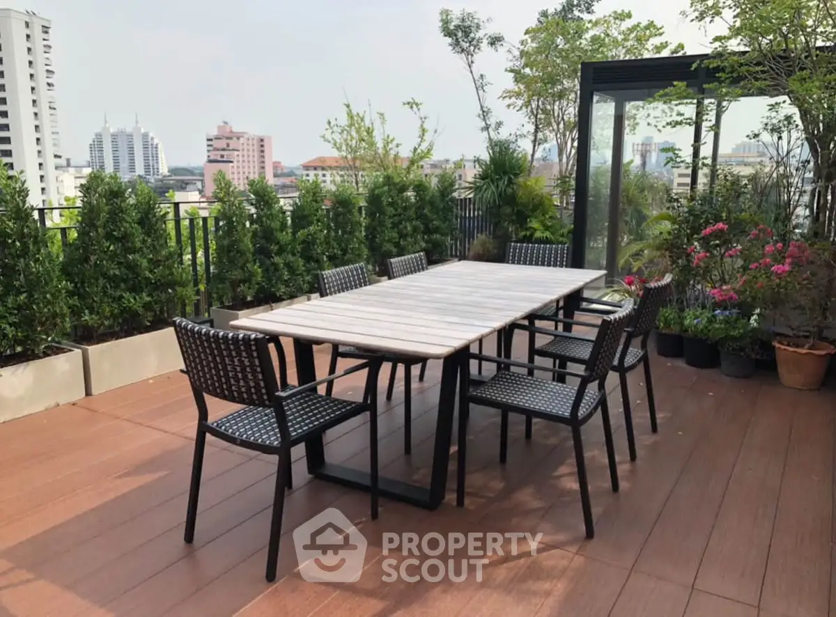 Stunning rooftop terrace with modern outdoor dining set and lush greenery, offering panoramic city views.
