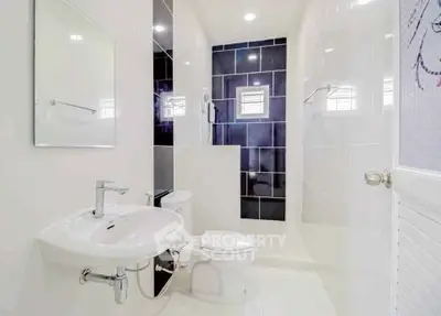 Modern white bathroom with sleek fixtures and black accent tiles