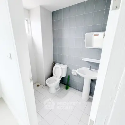 Modern minimalist bathroom with sleek white fixtures and gray tiled wall.