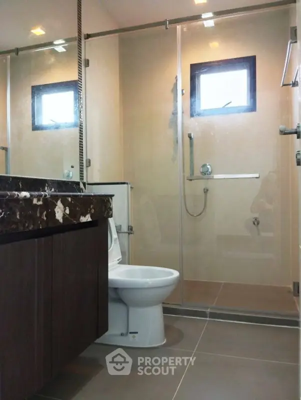 Modern bathroom with glass shower and sleek fixtures in contemporary home.