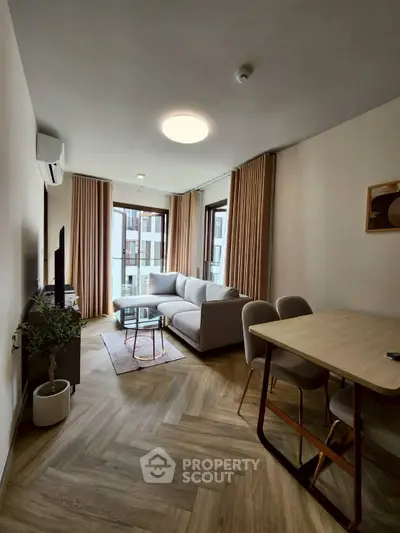 Modern living room with stylish decor and natural light, featuring a cozy sofa and dining area.