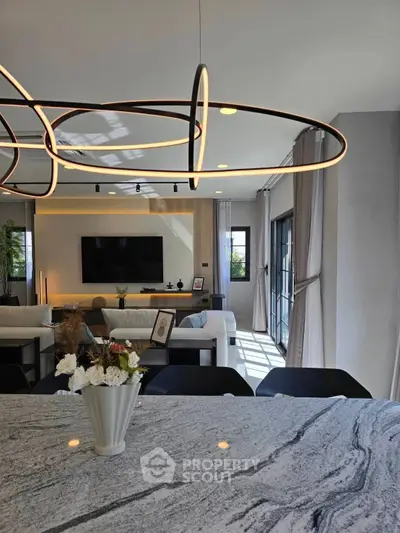 Modern living room with stylish lighting and open layout, featuring a marble countertop and large windows.