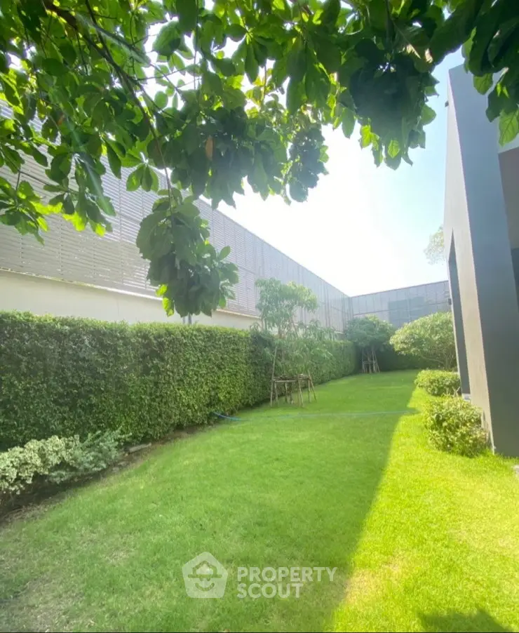 Lush green garden with manicured hedges and modern building facade, perfect for relaxation and outdoor activities.