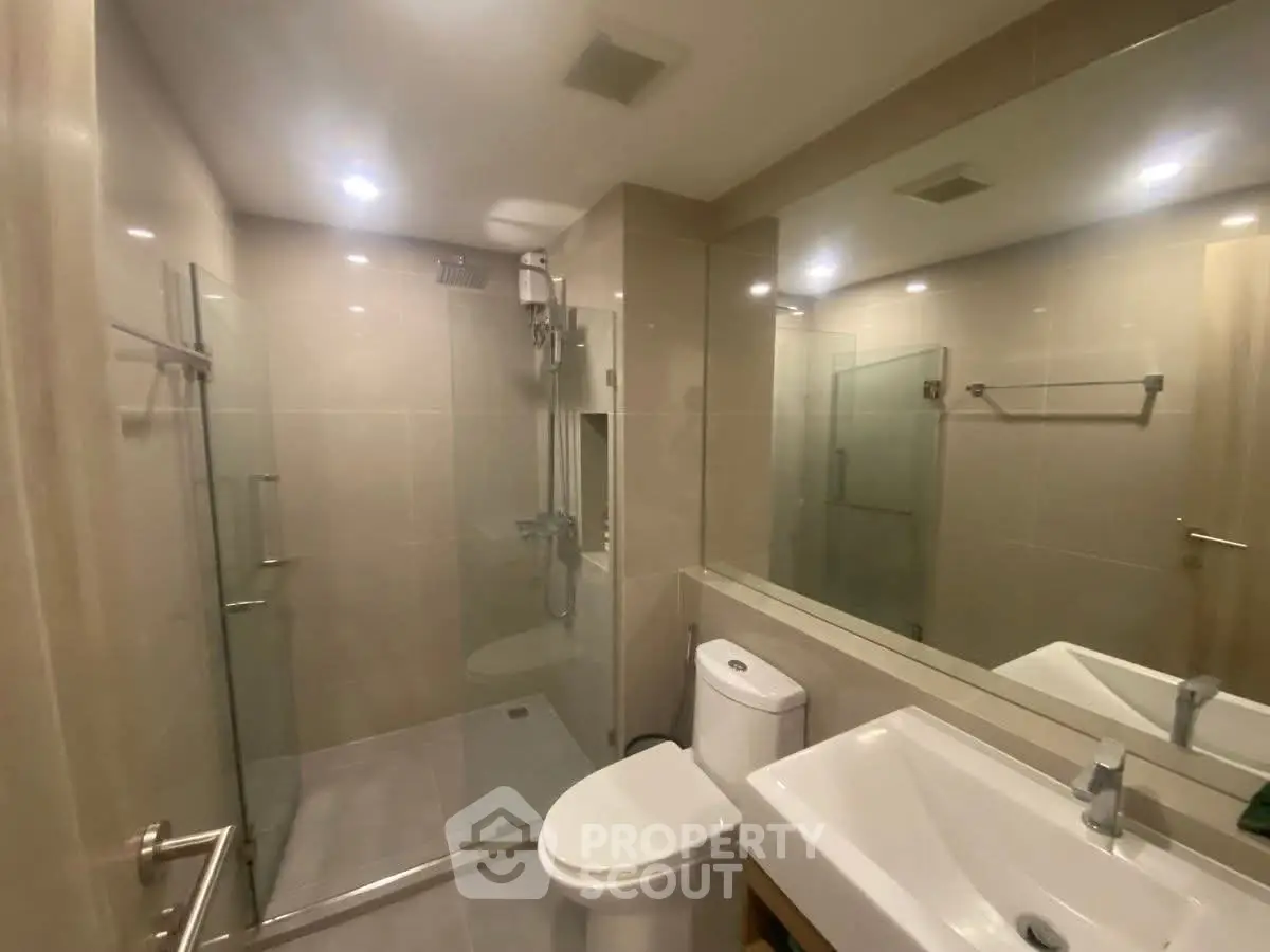 Modern bathroom with glass shower and sleek fixtures in a contemporary apartment.