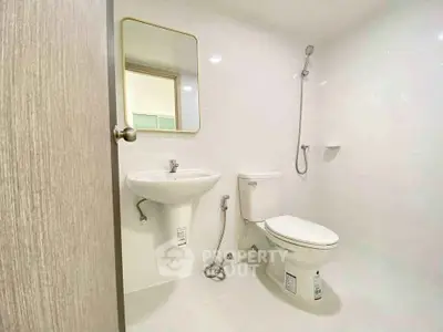Modern bathroom with sleek fixtures and minimalist design, featuring a wall-mounted sink and shower.