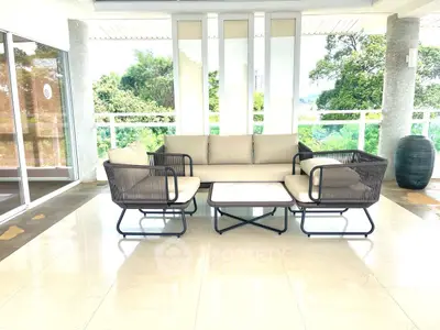 Spacious balcony with modern outdoor seating and lush greenery view.