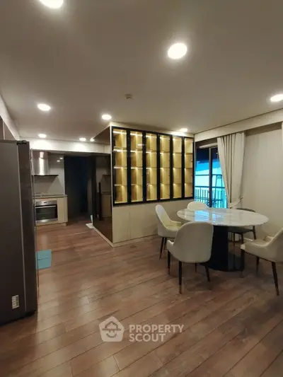 Modern open-layout kitchen and dining area with elegant lighting and wooden flooring