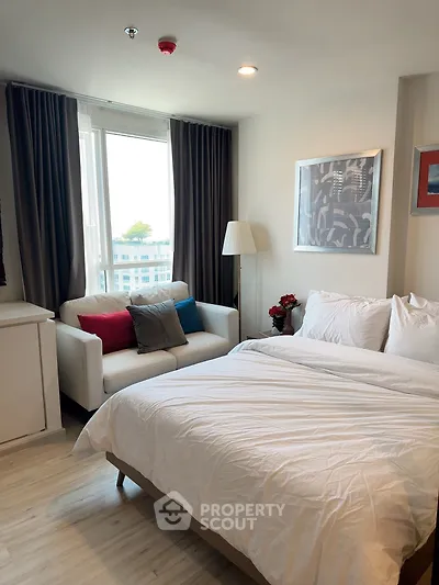 Cozy bedroom with modern decor, featuring a comfortable bed and stylish sofa near a large window.