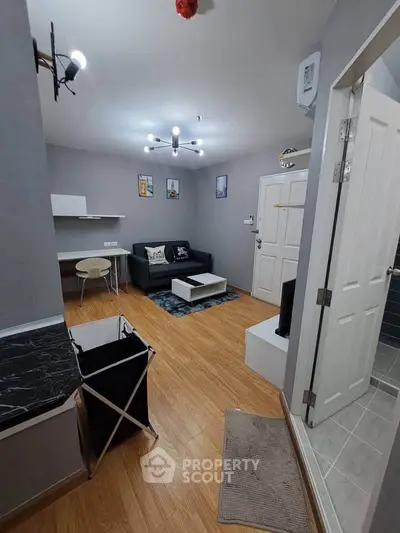 Modern living room with stylish decor and wooden flooring, featuring a cozy seating area and contemporary lighting.