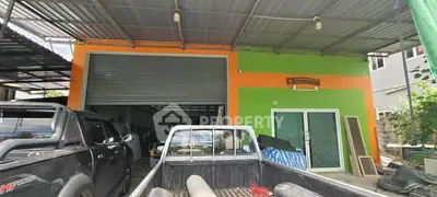 Industrial-style garage with vibrant orange and green facade, featuring spacious parking area.