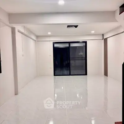 Spacious modern living room with sleek tile flooring and large sliding glass doors.