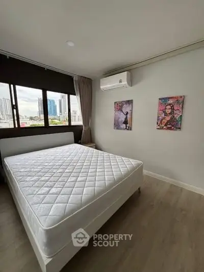 Spacious bedroom with city view and modern decor in urban apartment.