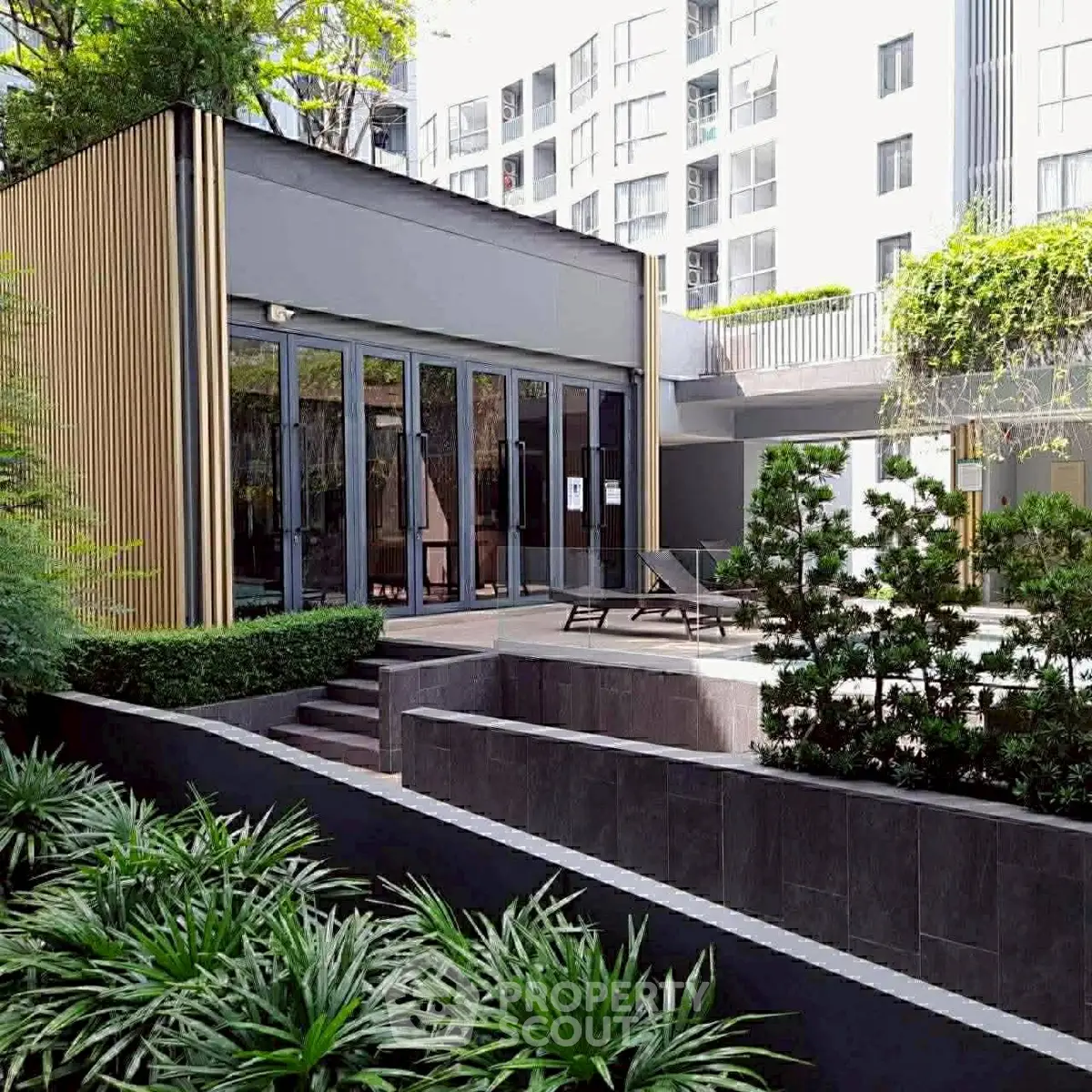 Modern apartment building with lush garden and stylish outdoor seating area.