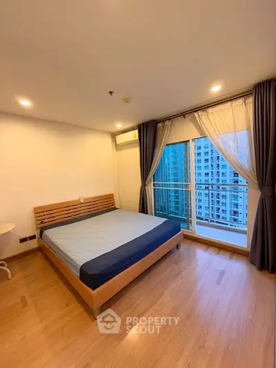 Spacious bedroom with large window and city view in modern apartment