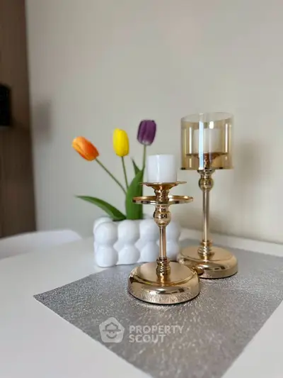 Elegant dining table with gold candle holders and colorful tulips centerpiece.