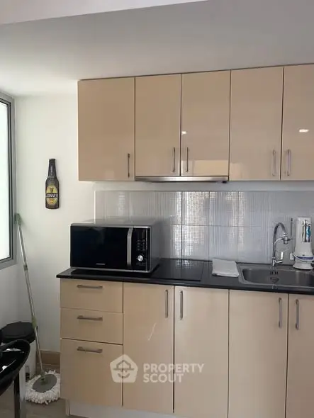 Modern kitchen with sleek cabinets and microwave, ideal for urban living.