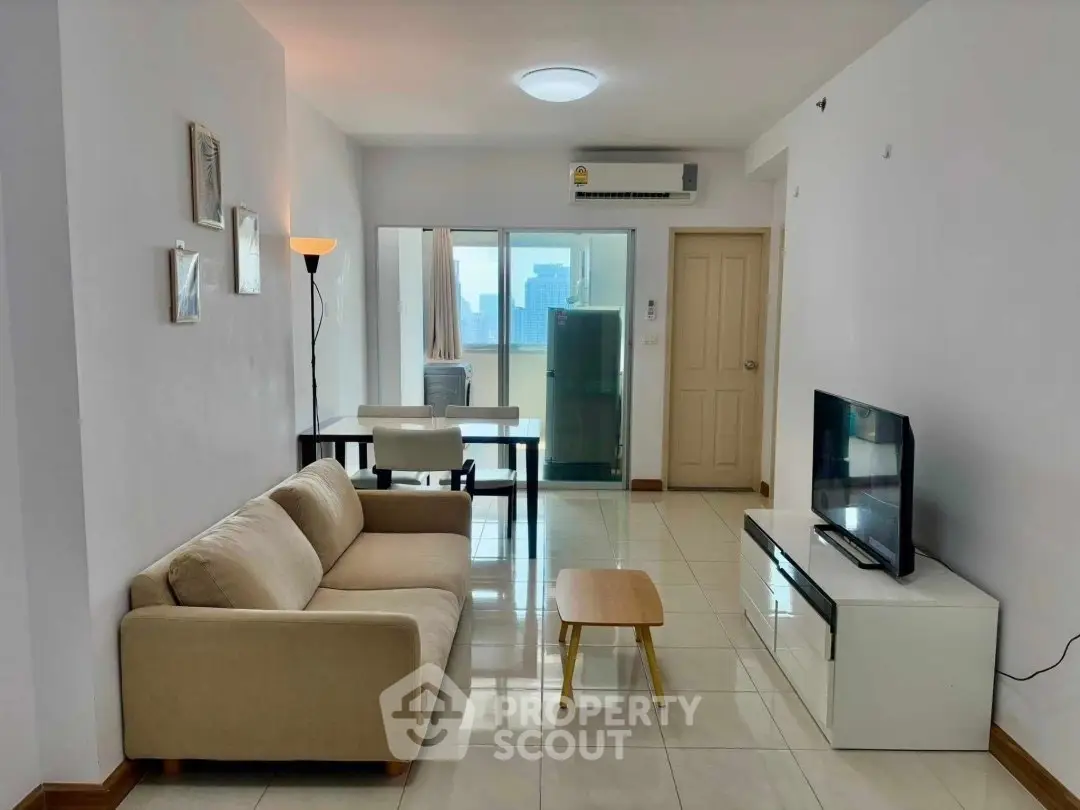 Modern living room with cozy sofa, TV, and dining area in bright apartment.