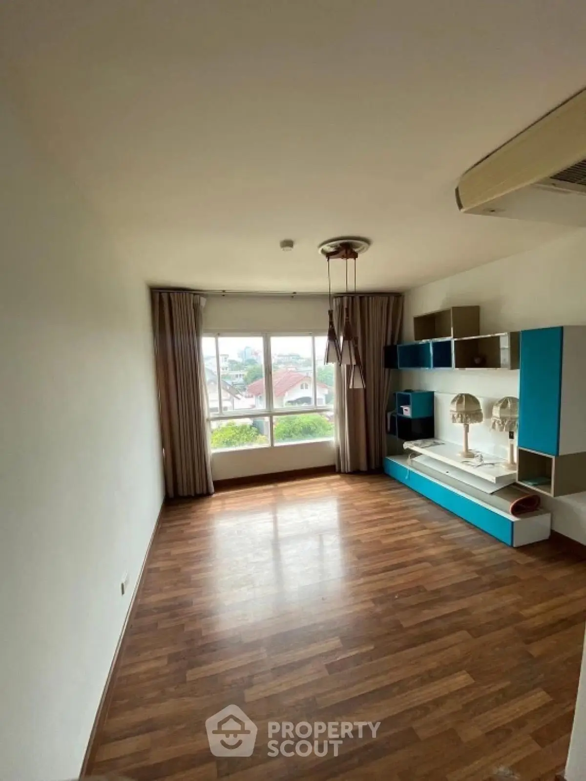 Spacious unfurnished room with large window and wooden flooring, ideal for customization.