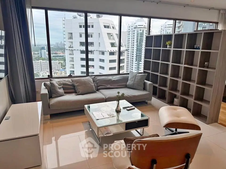 Modern living room with stunning city view, featuring sleek furniture and large windows.