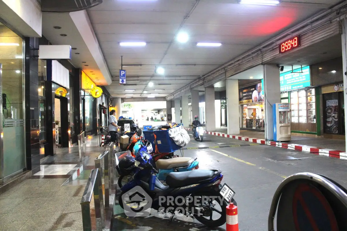 Modern parking area with motorbikes and shops, well-lit and spacious.