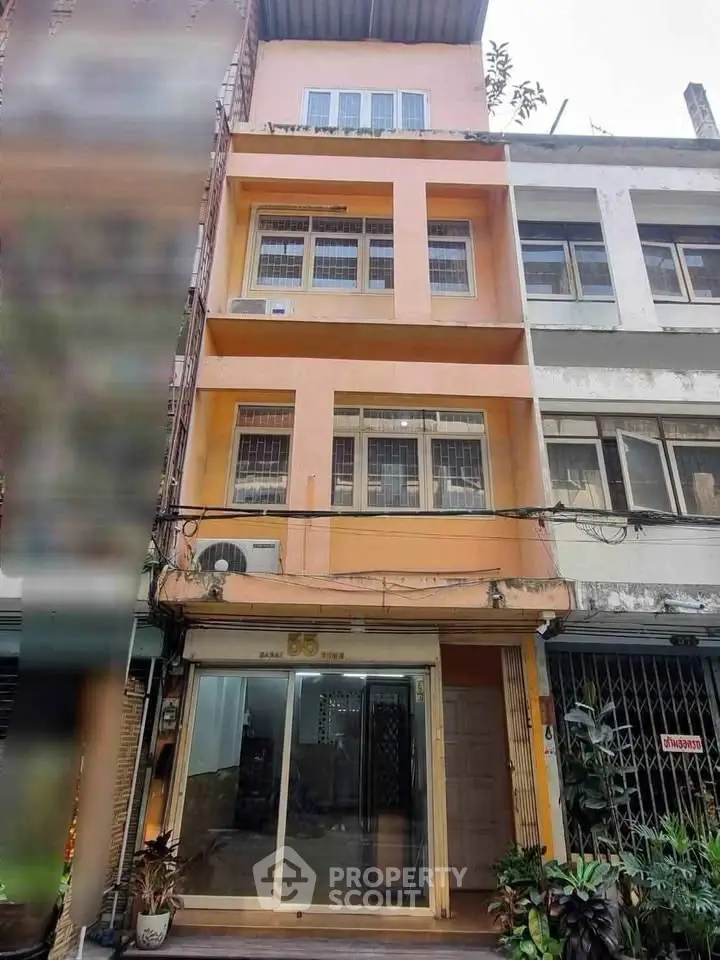 Charming multi-story building with a peach facade and large windows, ideal for urban living or business.