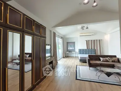 Spacious bedroom with elegant decor and large mirrored wardrobe in modern apartment.