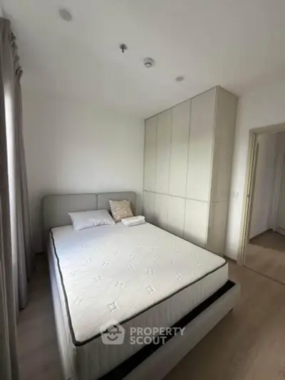 Modern bedroom with sleek design and ample natural light, featuring a comfortable bed and built-in wardrobe.