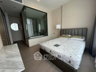 Luxurious modern bedroom with glass-walled ensuite, elegant decor, and natural light.