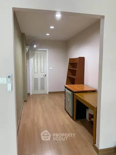 Spacious hallway with wooden flooring and built-in shelves, ideal for storage or study area.
