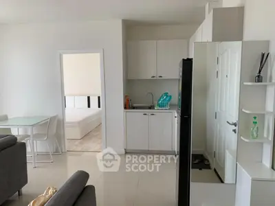 Modern open-plan living space with kitchen and dining area, featuring sleek furniture and neutral tones.