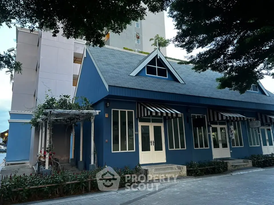 Charming blue building with striped awnings and lush greenery, perfect for commercial or residential use.