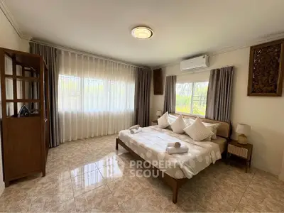 Spacious bedroom with elegant decor and large windows for natural light