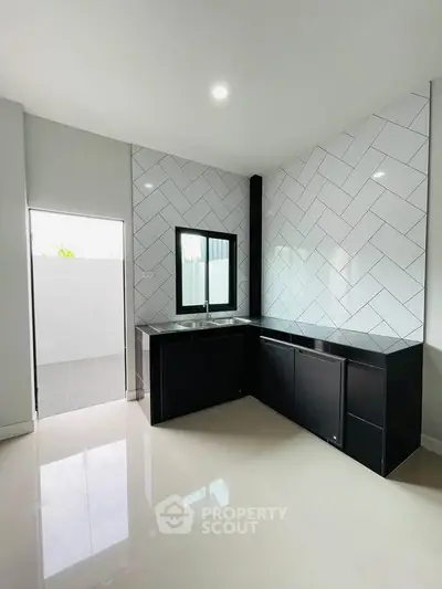 Modern kitchen with sleek black cabinets and stylish herringbone tile backsplash