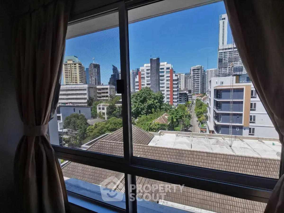 Stunning cityscape view from a high-rise apartment window, showcasing urban skyline and lush greenery.