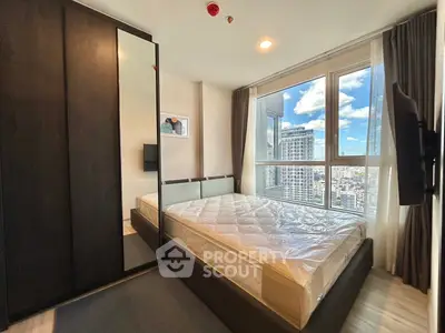 Modern bedroom with large windows offering stunning city views and sleek furnishings.