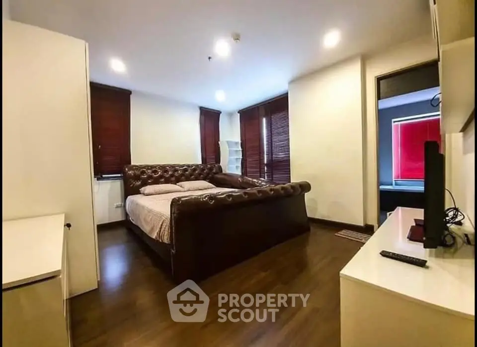 Spacious bedroom with elegant dark wood flooring and luxurious leather bed frame.