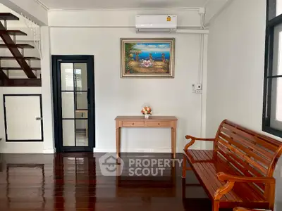 Charming living room with wooden floors, elegant bench, and wall art in a cozy home setting.