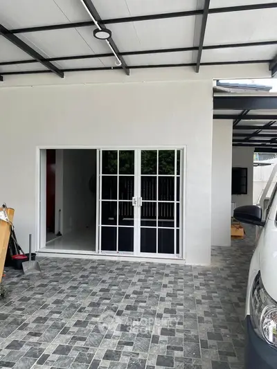 Modern home entrance with sliding glass doors and covered parking area.