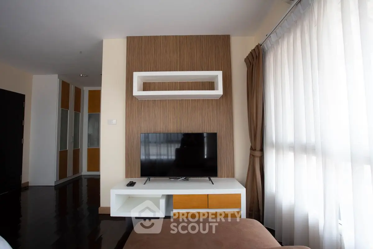 Modern living room with sleek TV stand and large window drapes