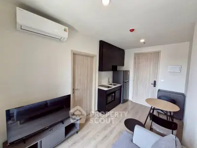 Modern compact living room with kitchenette, featuring sleek furniture and air conditioning.