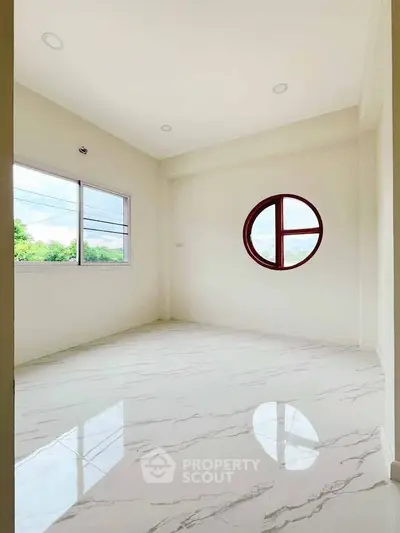 Bright empty room with unique round window and glossy marble floor, perfect for customization.