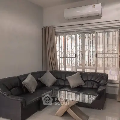 Cozy living room with black leather sectional and glass coffee table