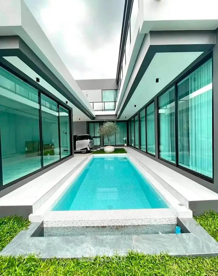 Luxurious modern home with sleek pool and expansive glass windows, perfect for contemporary living.