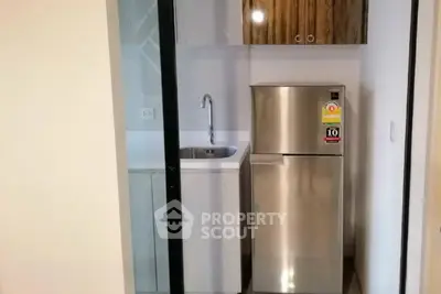 Compact kitchen with stainless steel fridge and modern cabinetry in a cozy apartment.